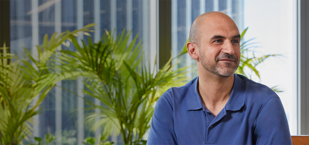 Ahmed regarde au loin vers la gauche en souriant.