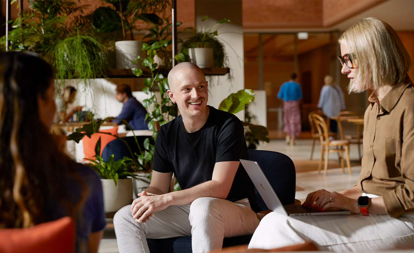 Trois membres Apple discutent, assis dans des fauteuils du Caffè Macs. L’une de ces personnes a un MacBook.