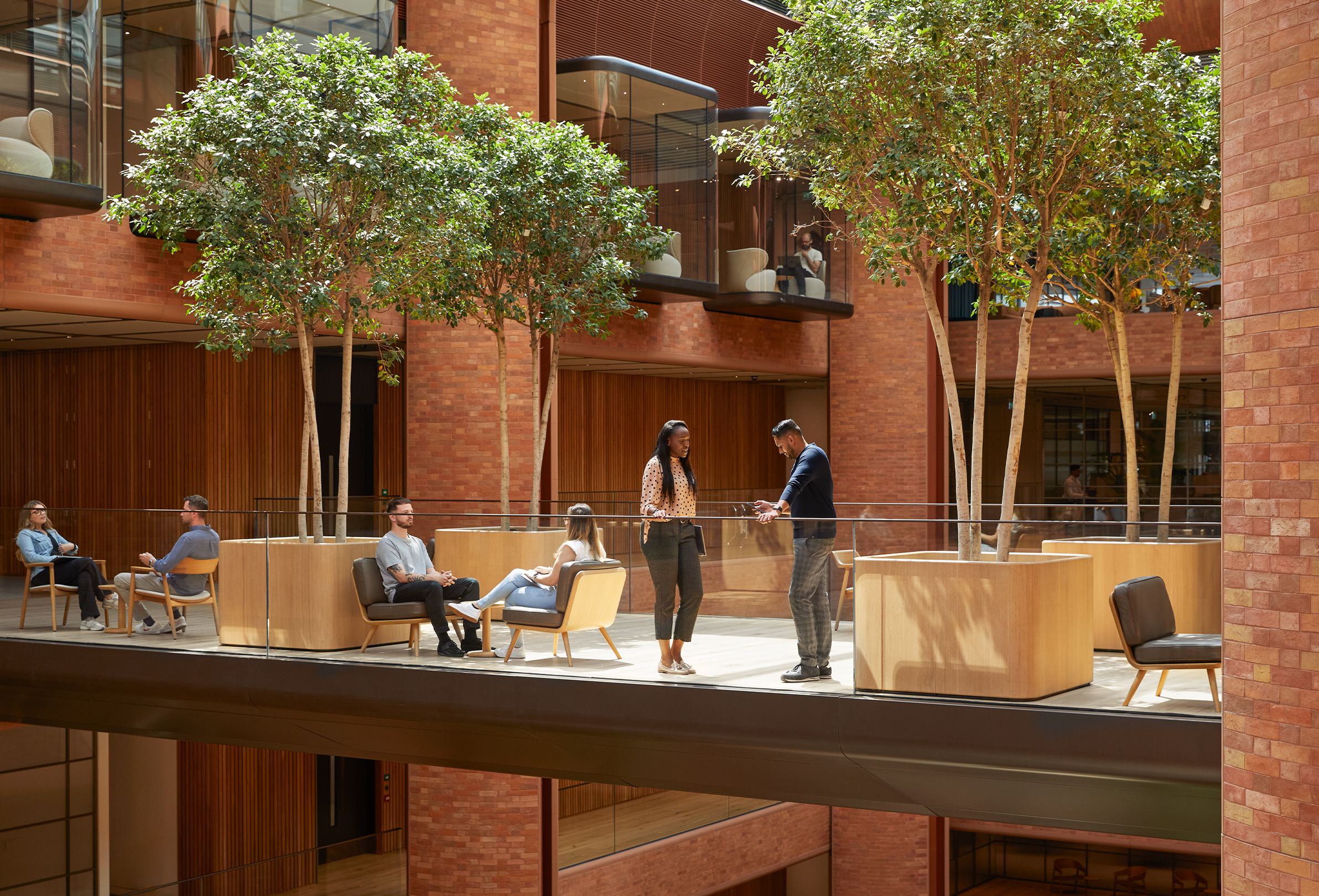 Des membres de l’équipe Apple discutent deux par deux, à plusieurs endroits dans l’atrium du site de Battersea.