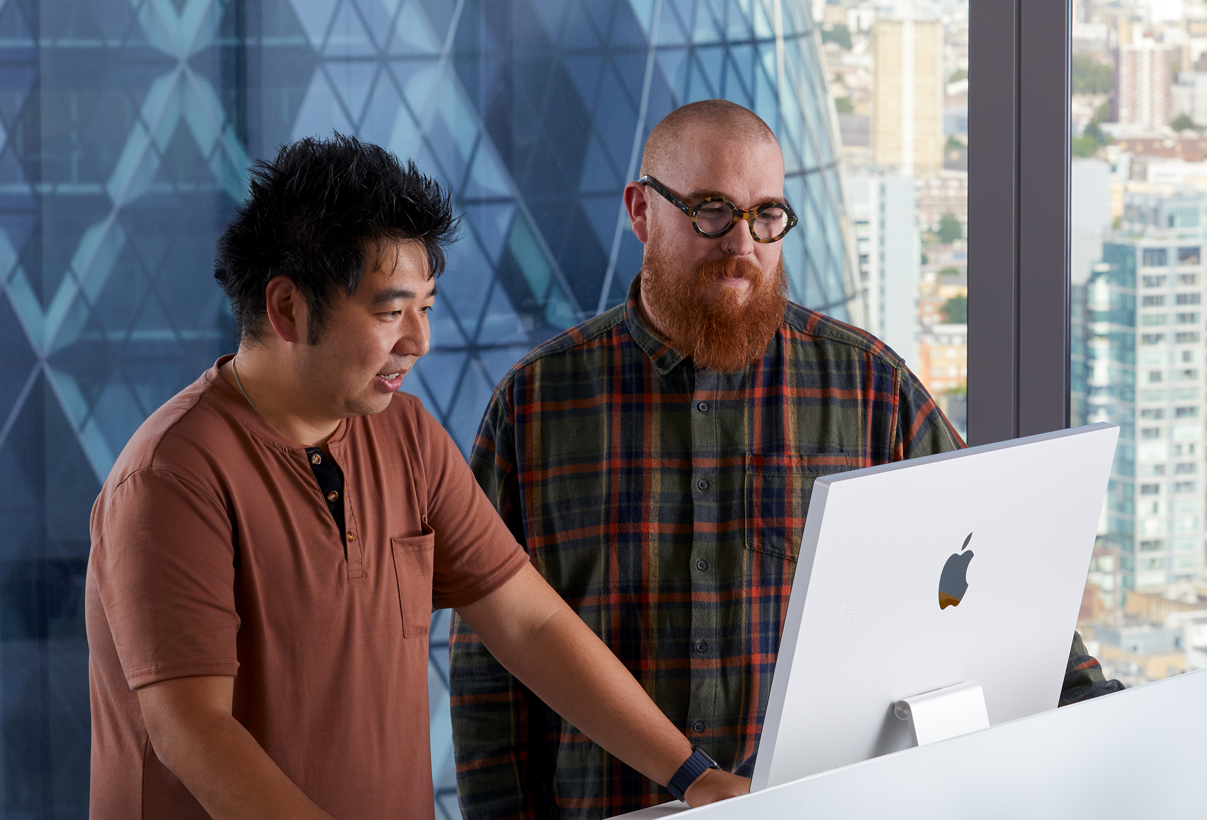 Deux employés Apple travaillent ensemble sur un iMac.