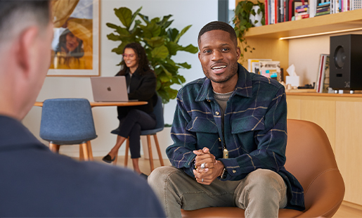 Justin est assis dans le salon d’un bureau et discute avec un collègue Apple.