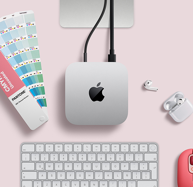 Vista desde arriba de un escritorio con un Mac mini color plata junto a unos AirPods, un Magic Keyboard color plata y blanco y una paleta de colores