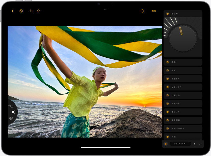 横向きのiPad Air。画面には、黄色と緑色の細長い布を持ち、夕暮れの海を背景に立っている少女の写真が表示されている