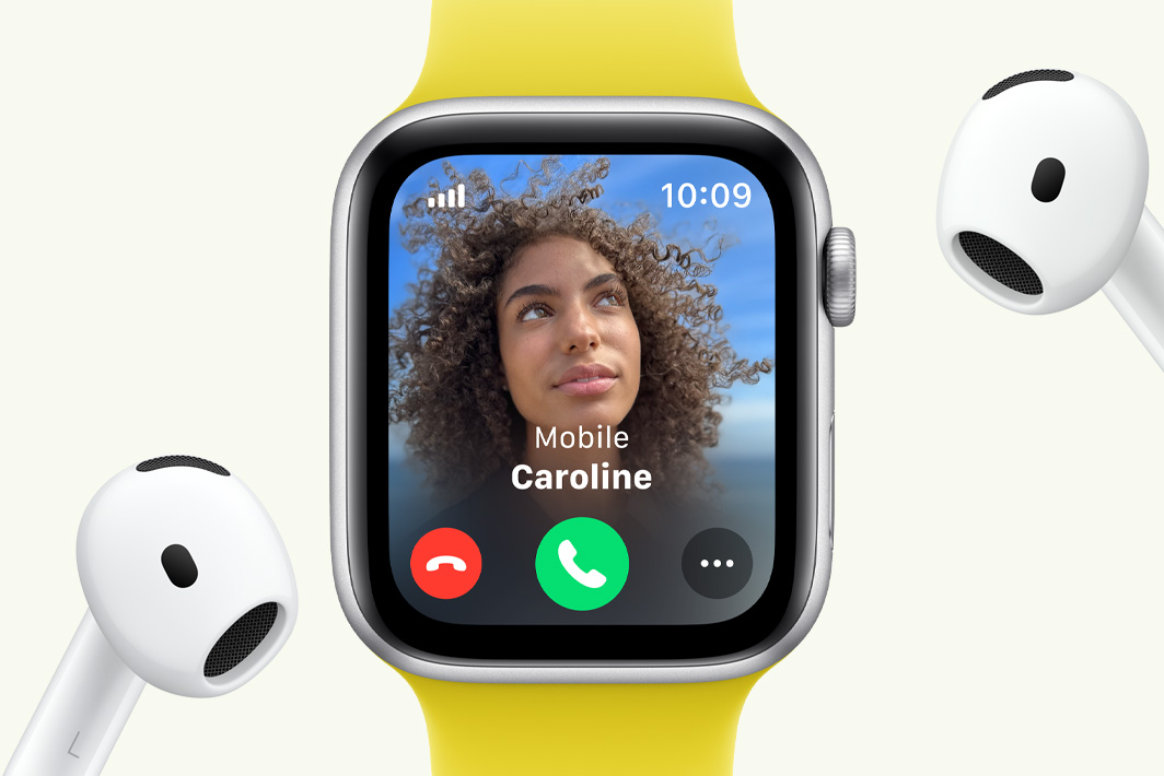 Et innkommende anrop vises på en Apple Watch SE ved siden av et par AirPods