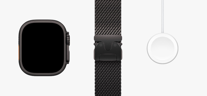 Stilt opp på rekke: maskinvaren i Apple Watch Ultra 2 vist forfra, Trail Loop i oransje og beige og en magnetisk hurtiglader-til-USB‑C-kabel.