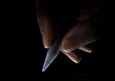 Uma mão segura a extremidade inferior do Apple Pencil Pro entre o dedo indicador e o polegar na posição de escrita.