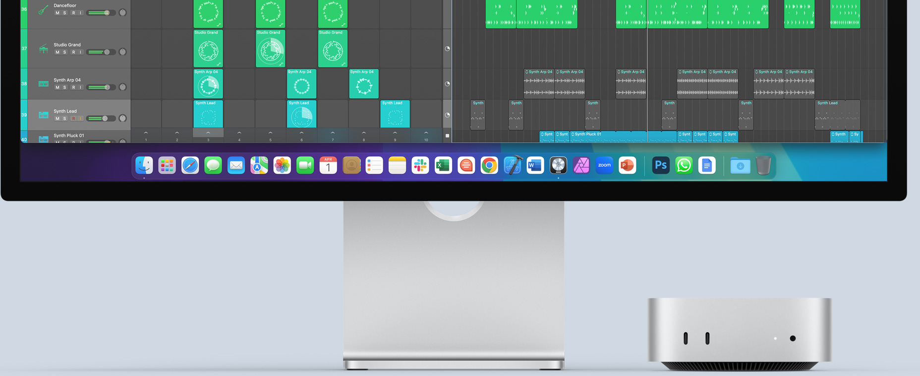 Imagem da frente do Mac mini prateado com portas na frente e uma luz indicadora de status, posicionado abaixo de um monitor Mac que mostra uma tela colorida e ícones de apps no Dock.