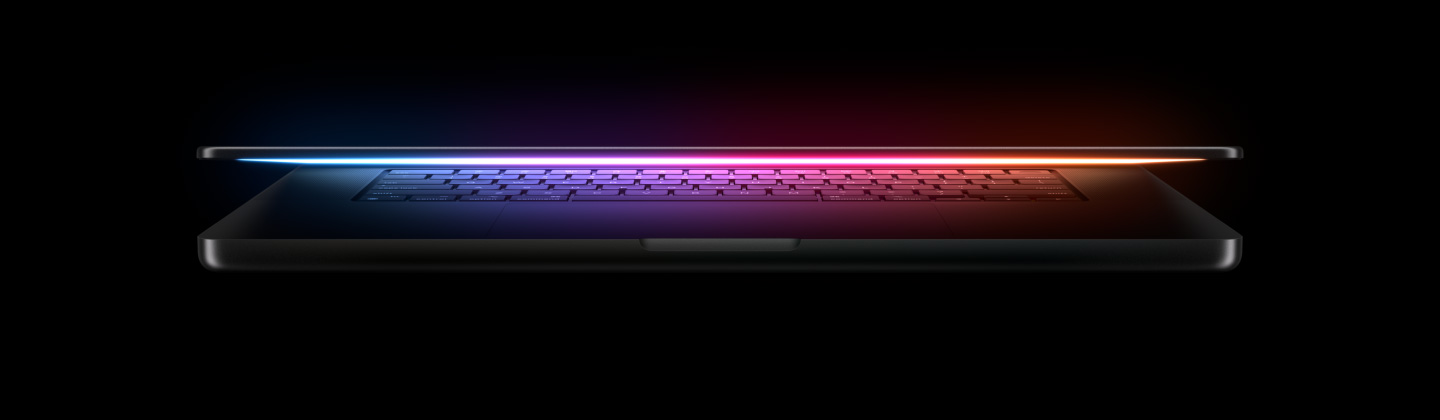 La pantalla de un MacBook Pro entreabierta refleja una luz multicolor sobre el teclado